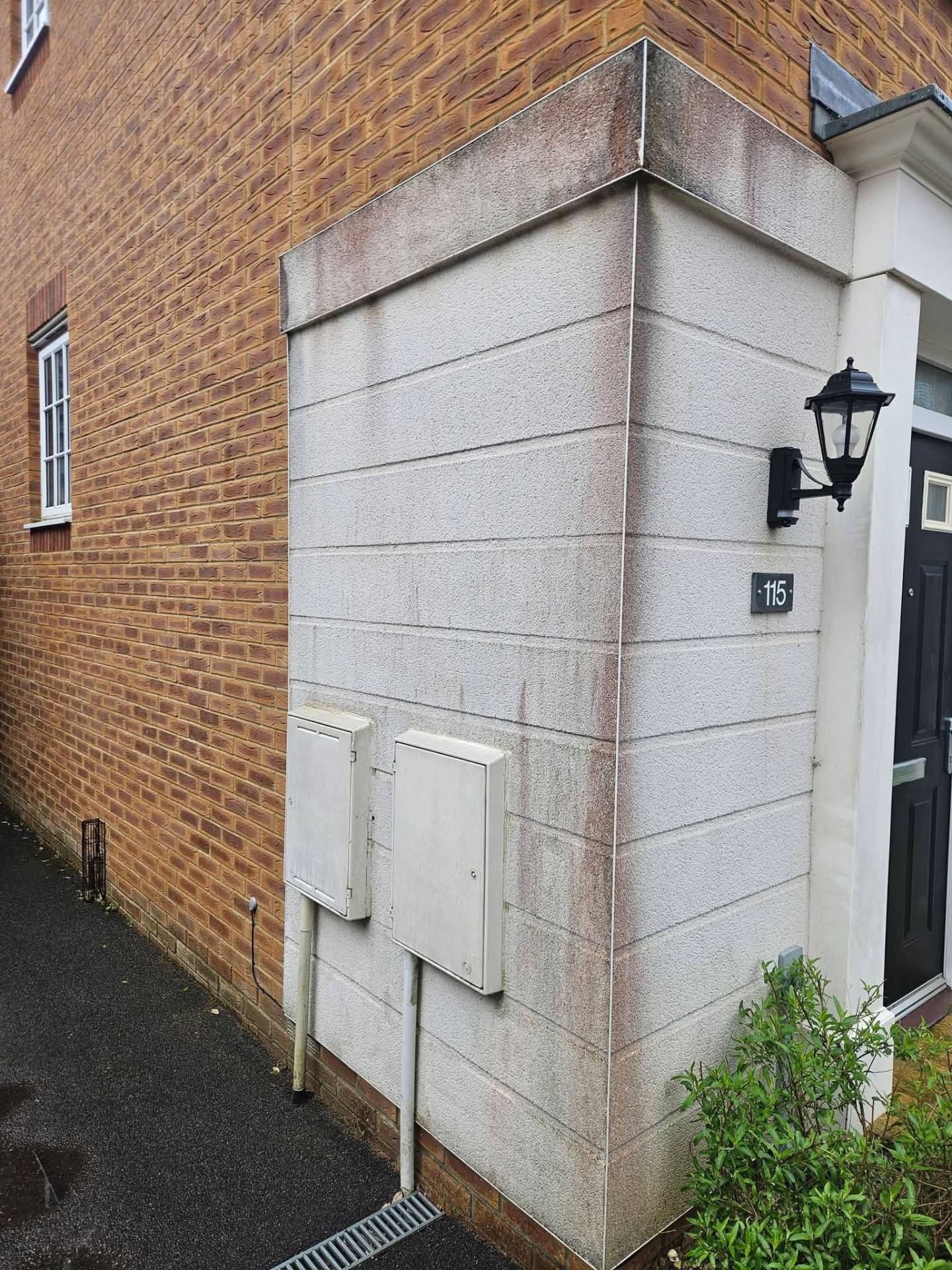 Rendered corner elevation streaked with algae and organic staining before softwash