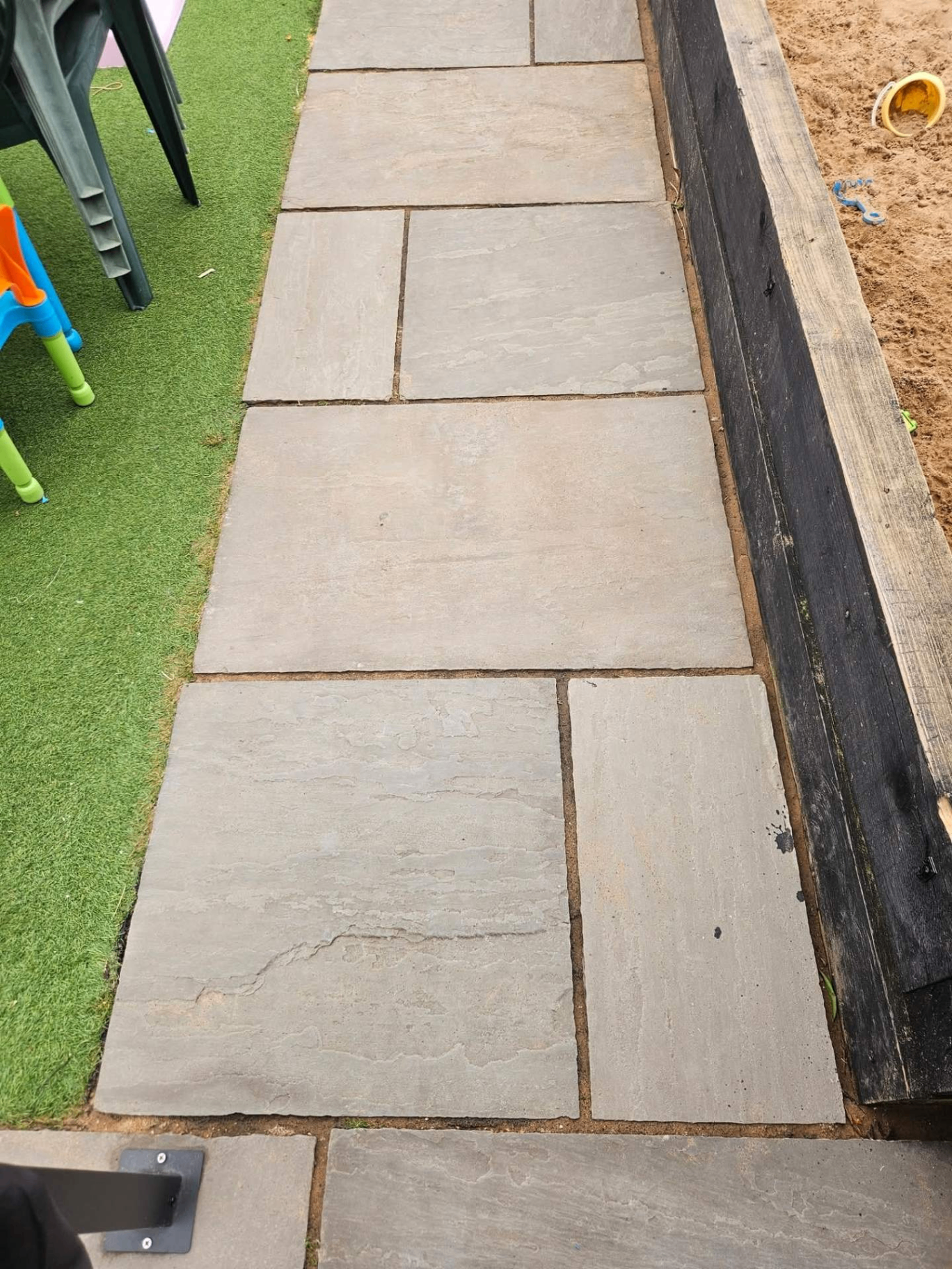 Indian sandstone path alongside artificial grass and raised sandpit — cleaned back to natural stone colour