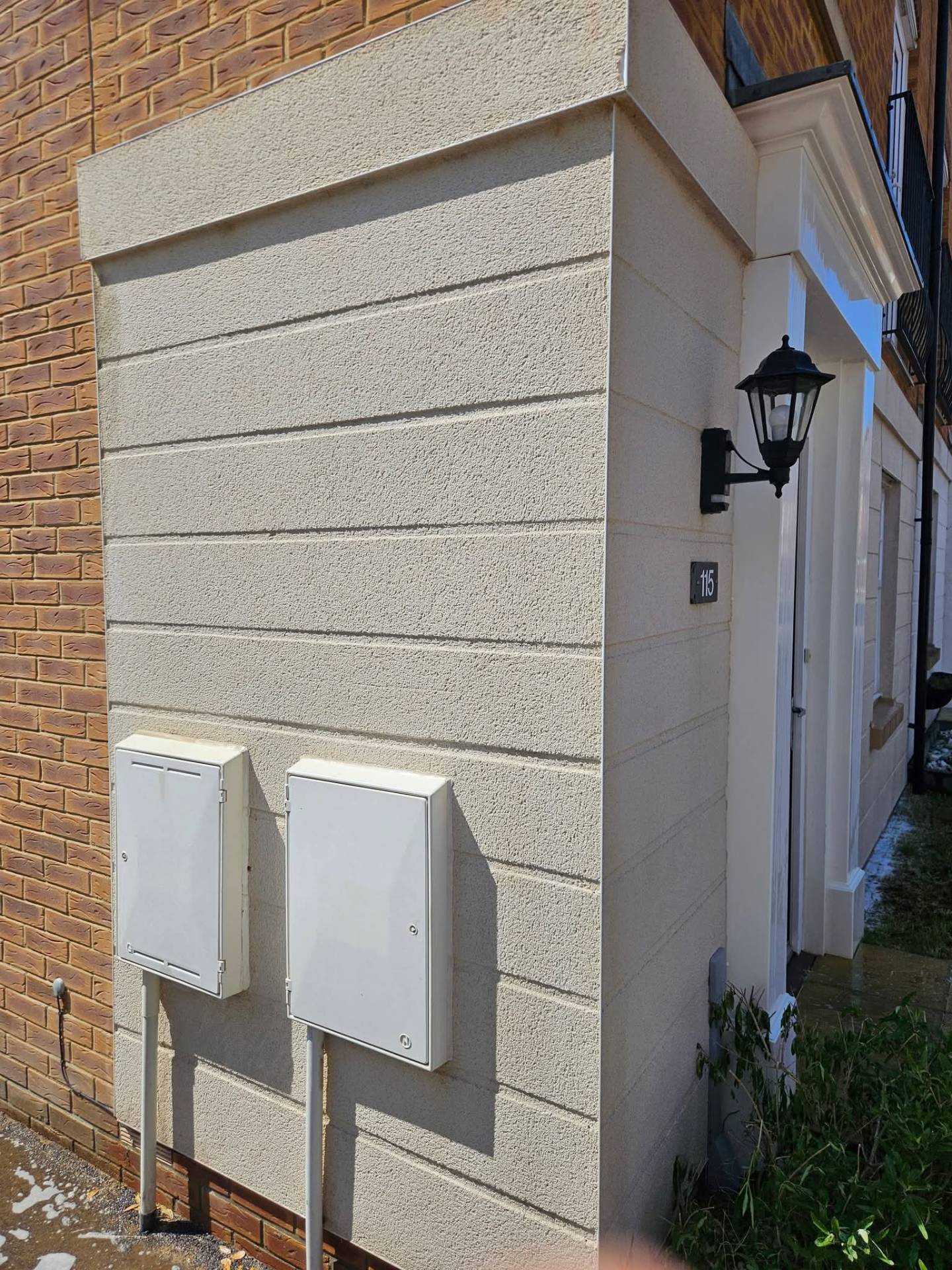 Same rendered corner returned to a clean, uniform finish after biocide softwash treatment